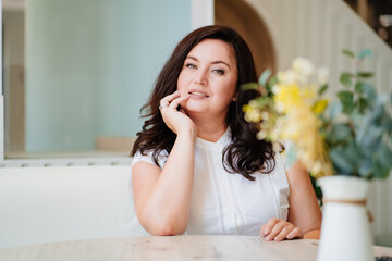 attractive woman in white clothes at the table in a light room. 