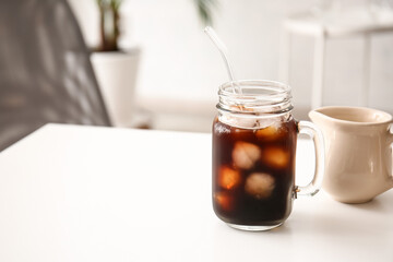 Mason jar of tasty ice coffee on table in office