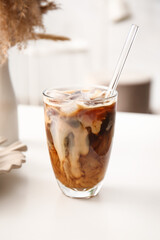 Glass of tasty ice coffee with milk on table