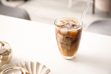 Glass of tasty ice coffee with milk on table