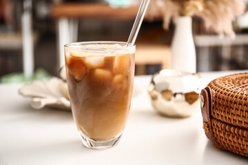 Glass of tasty ice coffee with milk on table