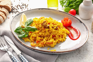 Plate with tasty pilaf on light background