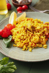 Plate with tasty pilaf on color wooden background