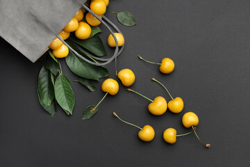 Bag with tasty sweet cherries on dark background