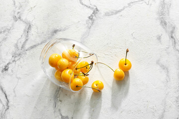 Glass with tasty sweet cherries on light background