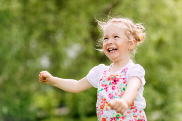 Happy laughing baby girl running in a clover fieldA happy laughing baby is running around the park or garden. Summer, summer time, happy days