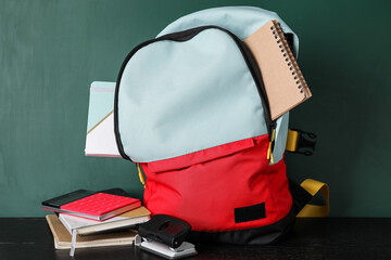 School backpack and stationery near blackboard