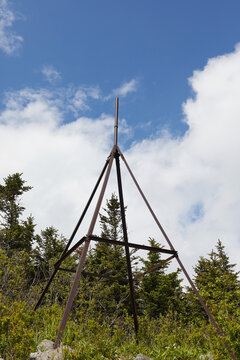Geodetic point against a background of clouds and forest