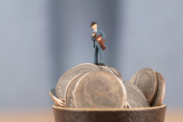 Businessman with full teacup above coins