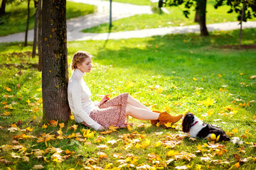 A woman and her pet dog of the Cavalier King Charles Spaniel breed in nature. A young beautiful...