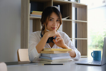 Cheerful young asian woman using laptop computer at home. Student female in living room. online learning, studying , online shopping, freelance, asean concept