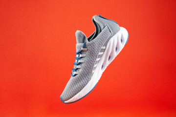 Stability and cushion running shoes. New unbranded running sneaker or trainer on orange background. Men's sport footwear.