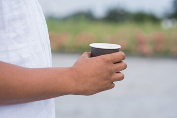 Close up of paper cup with coffee in hand of african american man