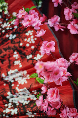 Delicate pink spring texture in oriental style with blurred flowers and black pattern on a red background