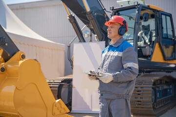 Concept man industrial 4.0 worker with online tablet. Bulldozer driver coal mine in uniform with...