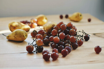 Grapes with ripe yellow pears on a wooden table