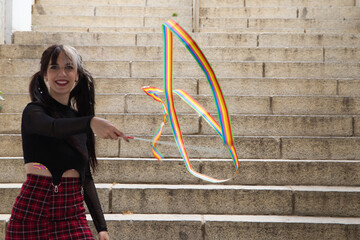 young and beautiful woman playing with a colourful rhythmic gymnastics ribbon. The woman is...
