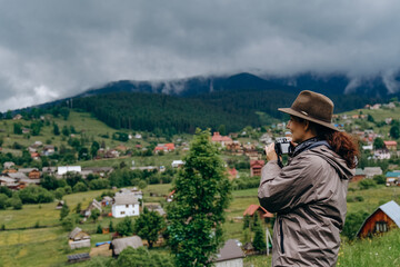 Woman photographer travels in the mountains in summer. Hiking in Europe. A woman photographs alpine landscapes.