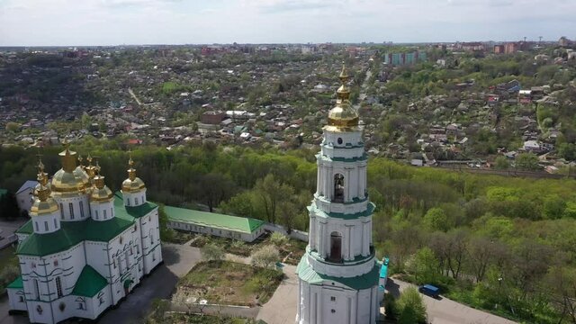 The territory of the church on a hill near the city. High white bell tower and golden domes with a cross
