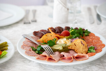 On a plate, an appetizer of sliced meat with croutons and vegetables.