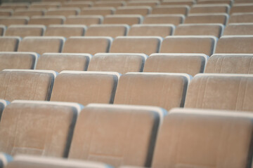 A row of empty beige chairs in the auditorium.