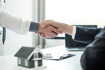 Businessmen and brokers' real estate agents shake hands after completing negotiations to buy houses insurance and sign contracts. Home insurance concept