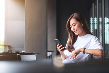 A beautiful young asian woman holding and using mobile phone - Powered by Adobe