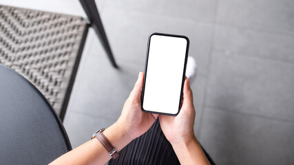 Top view mockup image of a woman holding mobile phone with blank white desktop screen