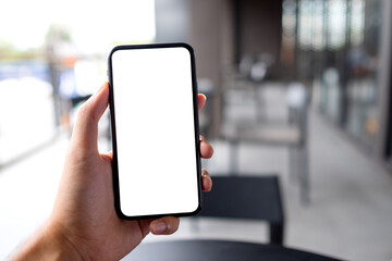 Mockup image of a man holding black mobile phone with blank white screen in cafe