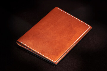 Brown leather wallet on a dark background.