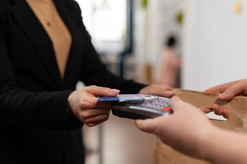 Close up of businesswoman holding plastic credit card in hand, paying for food delivery in company office. Using contactless pay for takeaway food. . Bringing tasty meal.