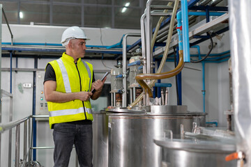 Engineers or factory managers wearing hard hats inspect the machines in the production line. The inspector opened the machine to test the system to meet the ISO standard. check and machine maintenance