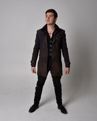 Full length portrait of a brunette man wearing black leather coat.  Standing pose isolated against...