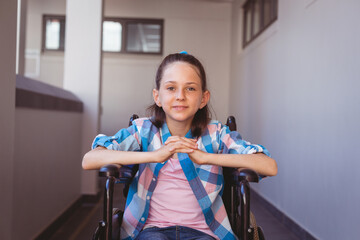 Portrait of smiling disabled caucasian schoolgirl sitting in wheelchair in school corridor