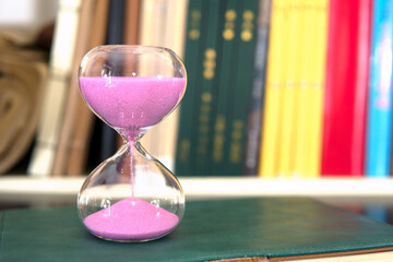 The hourglass in front of the bookshelf symbolizes cherishing time