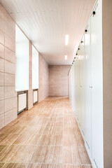 Indoors View of Long Industrial Tile Corridor With Metal Lockers.