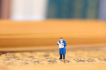 Miniature figures standing on bamboo slips and reading newspapers