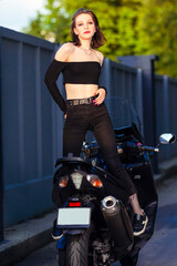 Obraz na płótnie Canvas Sensual Caucasian Female Motorcyclist Biker Standing On Sport Bike Back To Front Outdoors.