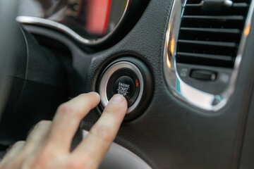 Male's finger pressing the start button, stop the engine in the luxury car