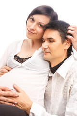Peaceful Lovely Dreaming Caucasian Couple with Pregnant Woman While Sitting Embraced Over White Background.