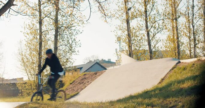 Crazy Teenager With Stunt Riding Skills On Low Bike, Rides Around Skatepark, Jumps Off Sloping Wall To Top Of Ramp And Slides Off, Performs Tricks On Bmx