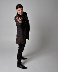 Full length portrait of a brunette man wearing black leather coat.  Standing pose isolated against...
