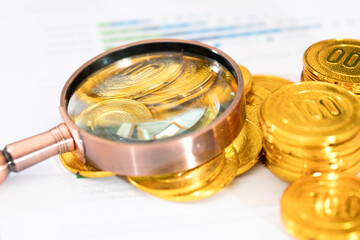 Magnifying glass and gold coins on documents
