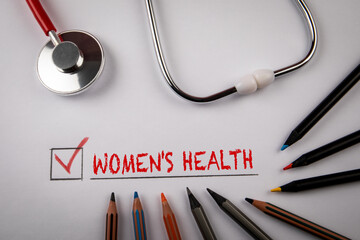 Women's health. Doctor's stethoscope and colored pencils on a white table