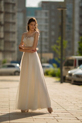 Naklejka premium beautiful woman in white long dress posing in the city