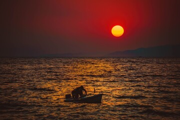 Pływający ludzie na morzu na tle ogromnego zachodzącego słońca © Michal45