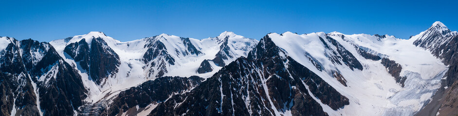 Obraz premium Panoramic view of the Aktru glacier, rugged rocky mountains with snowy slopes and Aktru peak 4044, Altai photo by drone