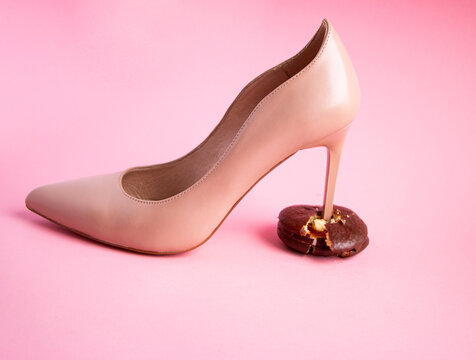heel stiletto heel of  womans leather beige shoe breaks chocolate sponge cake with filling into pieces and crumbs. concept of proper healthy nutrition, rejection of unhealthy and highcalorie foods.