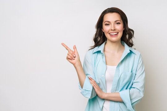Young woman smiling and gesturing to copy space.