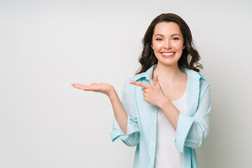 Young woman smiling and gesturing to copy space.